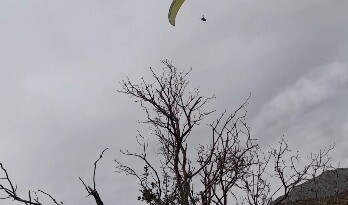 Gönülleri ısıtan davet: Yamaç paraşütçüsü işçilerin çay davetine kayıtsız kalmadı  (Fotoğraflı)  Fevzi Demircan MERSİN (İHA) – Mersin’de fidan dikimi yapan orman işçileri, yemek molası sırasında uçuş yapan yamaç paraşütçüsüne seslenerek çaya davet etti. Daveti karşılıksız bırakmayan paraşütçü iniş yaparak işçilerin yanına giderken ortaya çıkan samimi ve gülümseten anlar cep telefonu kamerasına saniye saniye yansıdı. Olay, Silifke ilçesine bağlı Yeşilovacık Işıklı mevkiinde meydana geldi. Ormanda fidan dikimi yapan işçiler, yemek molasında oldukları sırada üzerlerinden uçuş yapan yamaç paraşütçüsünü fark etti. Paraşütçünün kendilerine yakın mesafeden geçtiğini gören işçiler, seslenerek ‘gel çay içelim’ diyerek davette bulundu. Yapılan davete kayıtsız kalmayan yamaç paraşütçüsü Osman Doğan, işçilere havadan seslenerek ‘geliyorum’ diye yanıt verdi. Uygun bir noktaya iniş yapan Doğan, orman işçilerinin yanına giderek çay içti. Yaşanan bu samimi anlar, orman işçilerinin cep telefonu kamerasıyla kaydedilirken, görüntüler izleyenleri gülümsetti.  “Gel çay içelim diye seslendiler, ben de geliyorum dedim” Helix Paragliding Spor Kulübü yamaç paraşütçüsü Osman Doğan, uçuşun son bölümünde iniş planlaması yaptığı sırada aşağıda orman işçilerinin yemek molasında olduğunu ifade etti. Doğan, “Tam inişi planlarken aşağıdan bir seslenme oldu. ‘Gel çay içelim’ diye bağırdılar. Aslında yönüm orası değildi ama böyle bir daveti geri çevirmek istemedim. Havadan ‘geliyorum’ diye seslendim ve bulundukları bölgeye indim” diye konuştu. İndikten sonra oldukça sıcak bir ortamla karşılaştığını ifade eden Doğan, “Çok hoşgörülü insanlardı. Hava da oldukça soğuktu, çay gerçekten çok iyi geldi. Bir süre sonra kulübümüzden başka arkadaşlarımız da yanımıza geldi. Hep birlikte çay içtik, ardından onlar işlerine devam etti” ifadelerini kullandı.  “Bu sporu tanıtmak istiyoruz” Yaşanan durumun kendisi için de sürpriz olduğunu belirten Doğan, “Genelde indiğimiz yerlerde çocuklar daha çok ilgi gösterir ama bu kez çok samimi bir davet vardı. Yüksekte olmama rağmen seslerini bana duyurmayı başardılar. Yamaç paraşütü ülkemizde henüz çok yaygın bir spor değil. İnsanlar merak ediyor” dedi. Türkiye’nin farklı bölgelerinde de benzer güzel yaklaşımlarla karşılaştıklarını dile getiren Doğan, “Bazen hava şartları nedeniyle planlanmamış yerlere inmek zorunda kalıyoruz. İnsanlar bizi araçlarıyla alıyor, evlerine davet ediyor ya da ekip arkadaşlarımız gelene kadar misafir ediyor. Ülkemizin her yerinde büyük bir saygı ve hoşgörü görüyoruz. Bu konuda herkese teşekkür ediyoruz” diyerek bilgi verdi.